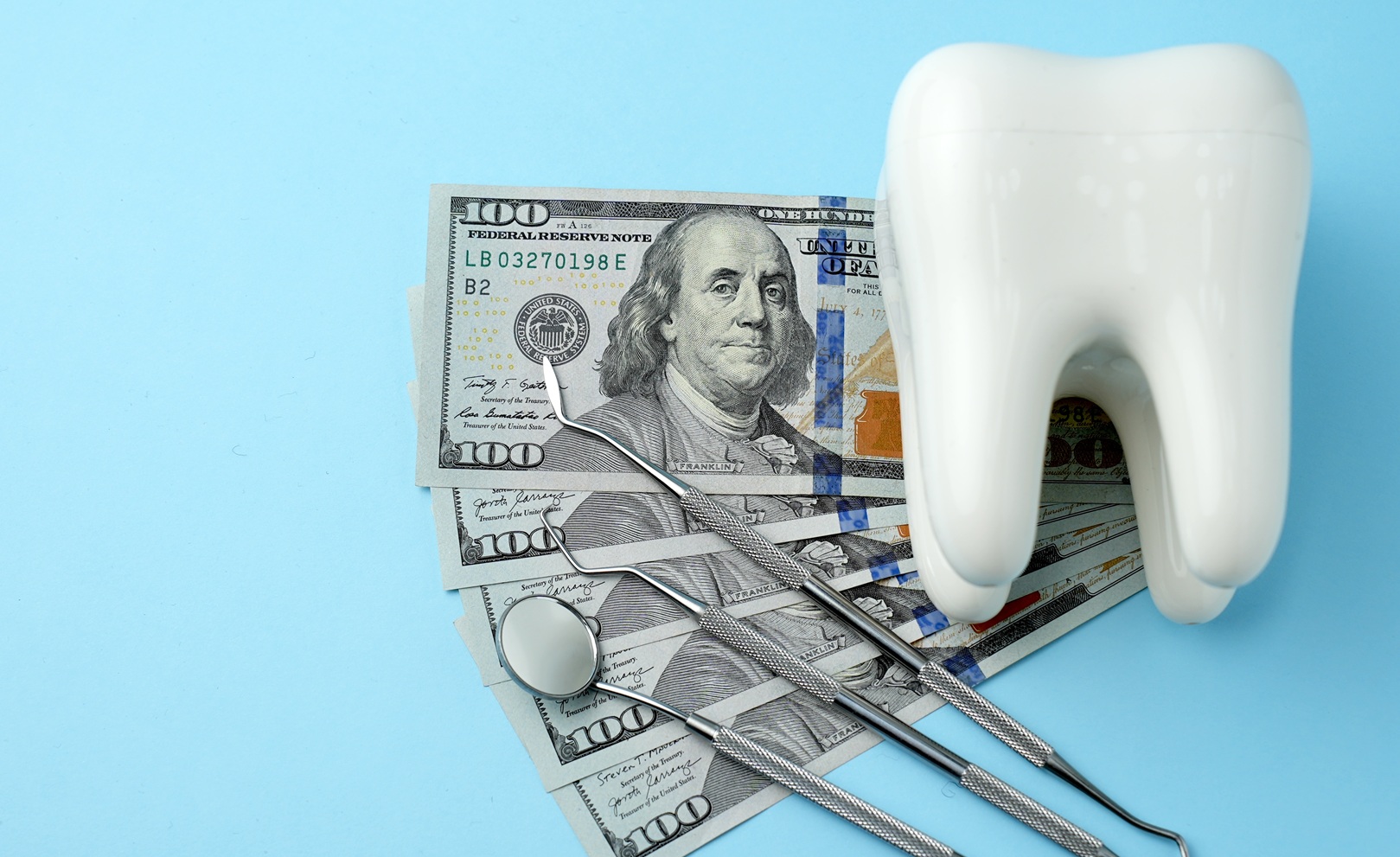 Dental Service, Insurance and dentist bill cost. The concept of saving money for dental treatment. Dollar money bills and tooth model on a bluebackgound with copy space