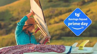 A women wearing a Patagonia Nano Puff insulated jacket lifts a surfboard in the early morning light