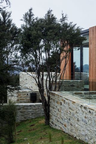 Benched into the rock, the house's stone base drives out of the ground to create a new landscape