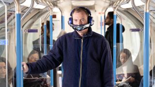 a man wearing the dyson zone air purifying headphones on a subway train