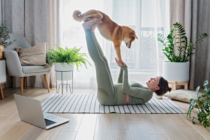 Woman working out at home with her dog
