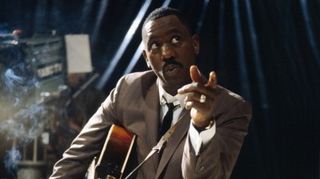 American jazz guitarist Wes Montgomery (1923-1968) posed smoking a cigarette with a Gibson L-5 semi acoustic guitar in a television studio during a recording for the television series 'Tempo' in 1965