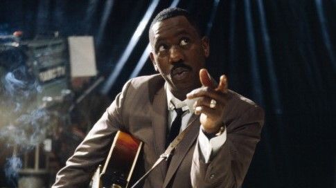 American jazz guitarist Wes Montgomery (1923-1968) posed smoking a cigarette with a Gibson L-5 semi acoustic guitar in a television studio during a recording for the television series &#039;Tempo&#039; in 1965