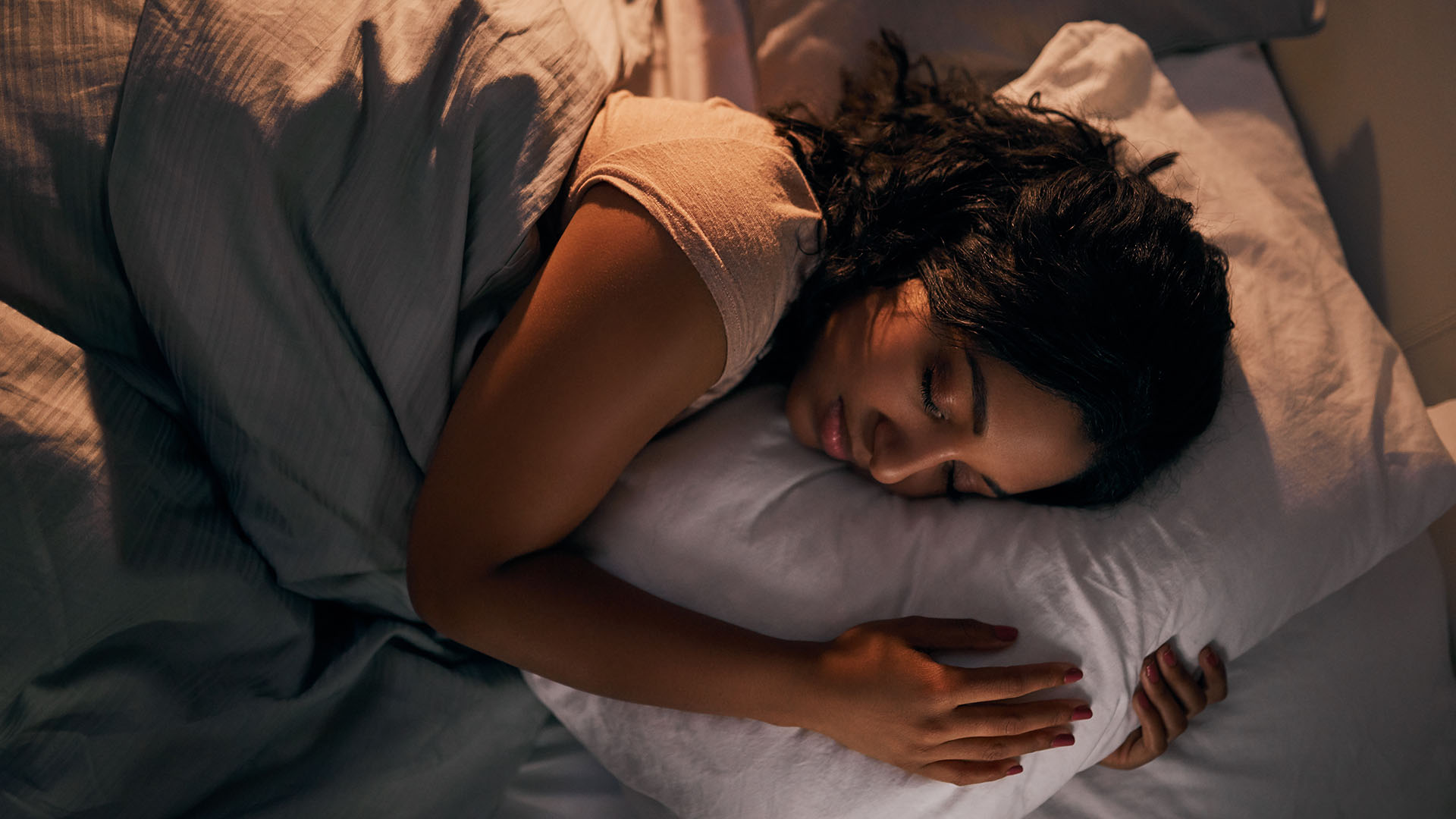 Woman sleeping on her side embracing a pillow