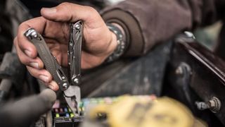 A close-up shot of a man's hands using the Leatherman Wingman multi-tool.