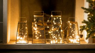 Lanterns filled with LED fairy lights used as simple Christmas decorating idea in a fireplace