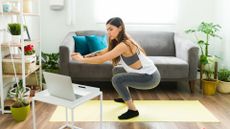 woman in squat position on a yoga mat in her living room