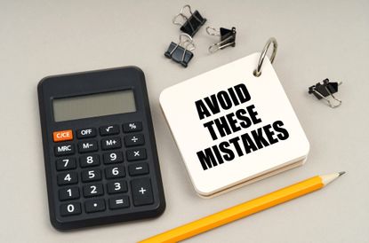 On a gray surface, a calculator, a pencil and a notepad with the inscription - Avoid These Mistakes