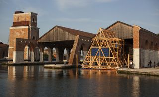 A wooden, triangular structure floating outside the gallery