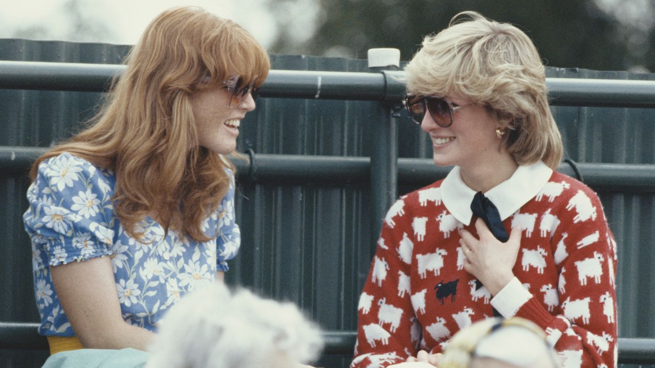 Sarah Ferguson sitting and talking to Princess Diana, who is wearing a red sheep sweater, smiling at a polo match