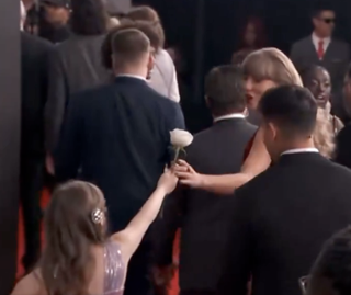 Taylor Swift accepting a white rose from a little girl wearing a pink sequined dress