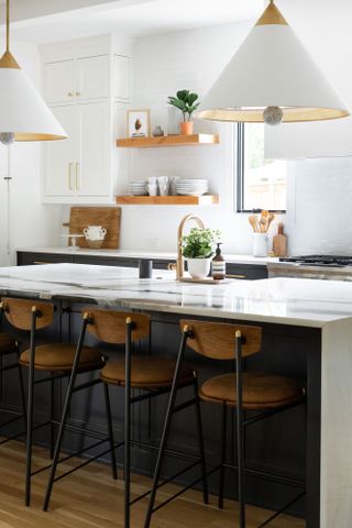 Black kitchen island with white waterfall counter, black and leather bar stools and large statement white pendant lights
