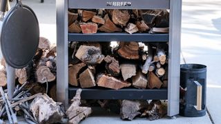 Breeo Live-Fire Grill with a fully stocked wood shelf