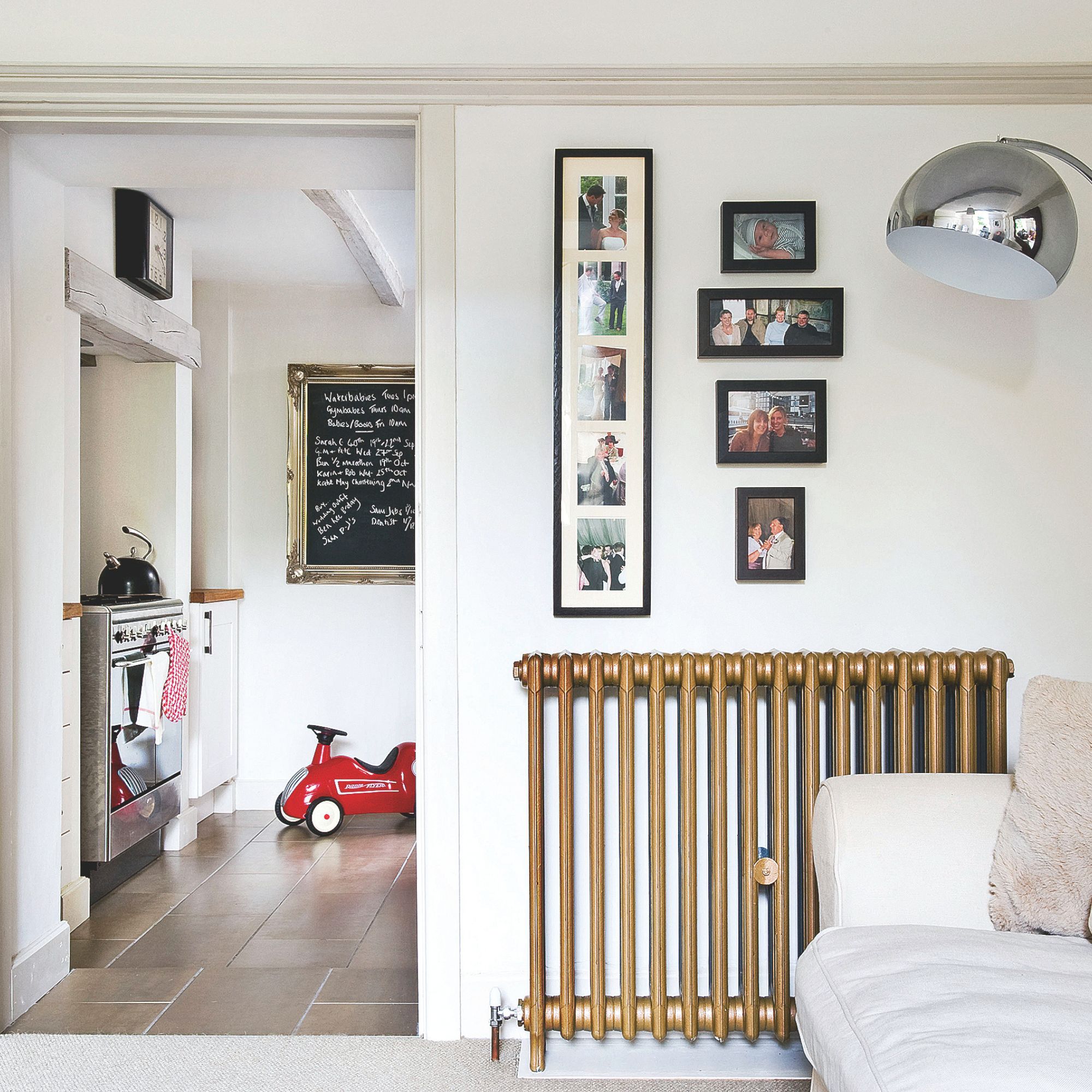 Gold cast iron radiator on wall of living room, next to a doorway that leads to a kitchen