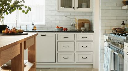 a white kitchen with drawers, tiles, and objects on the countertops