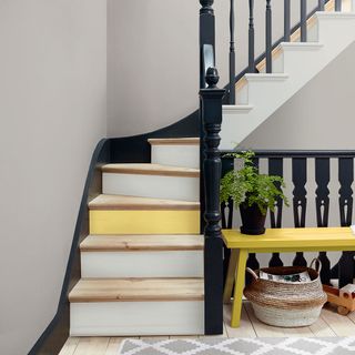 staircase with a black painted banister and yellow and white steps