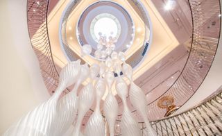Installation of white beehive-like shapes hanging from the spiral staircase at Fortnum & Mason