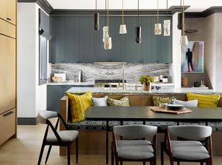 Open plan kitchen with grey cabinets, yellow cushions and marble worktop