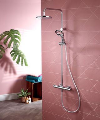 Geometric pink shower tiles in bathroom with palm plant and chrome shower fitting