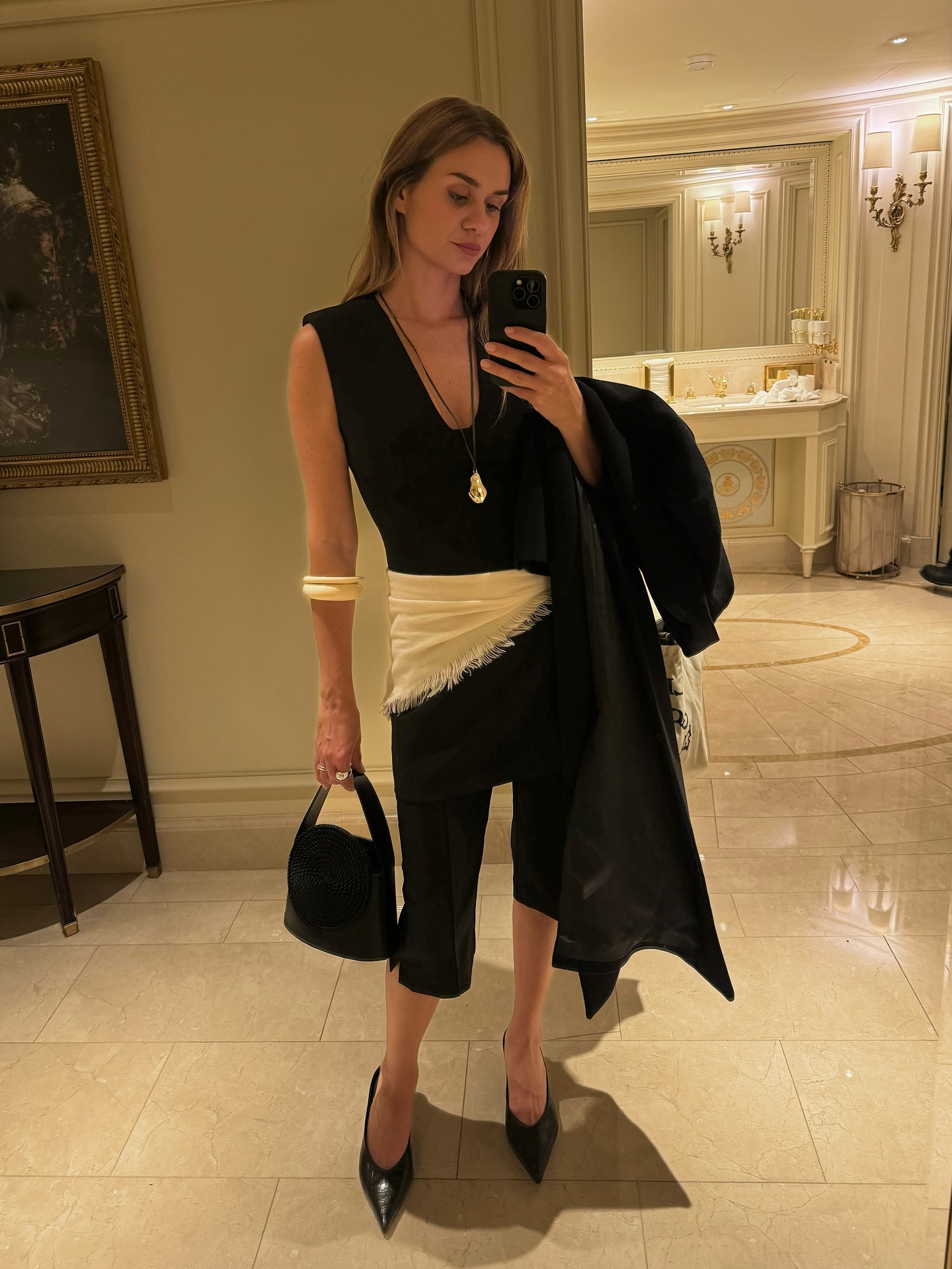 An image of @annelauremais wearing capri trousers, one of the best anti-jeans summer trouser trends, with a tank top and scarf belt.