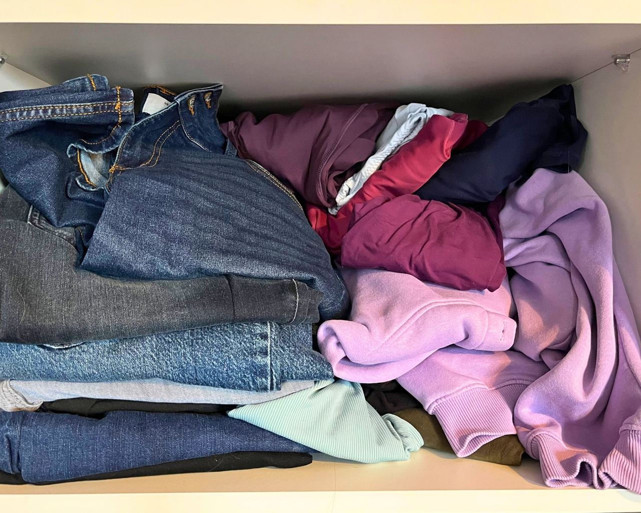 Messy shelf of jeans and tops before using my air folding method