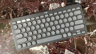 The Logitech Pebble Keys 2 K380S keyboard seen from above on a marble worktop.