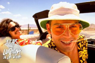 Raul sitter i en cabriolet på vei til Vegas med solbriller, solhatt og en sigg i munnen, med Dr. Gonzo i bakgrunnen, bak rattet.