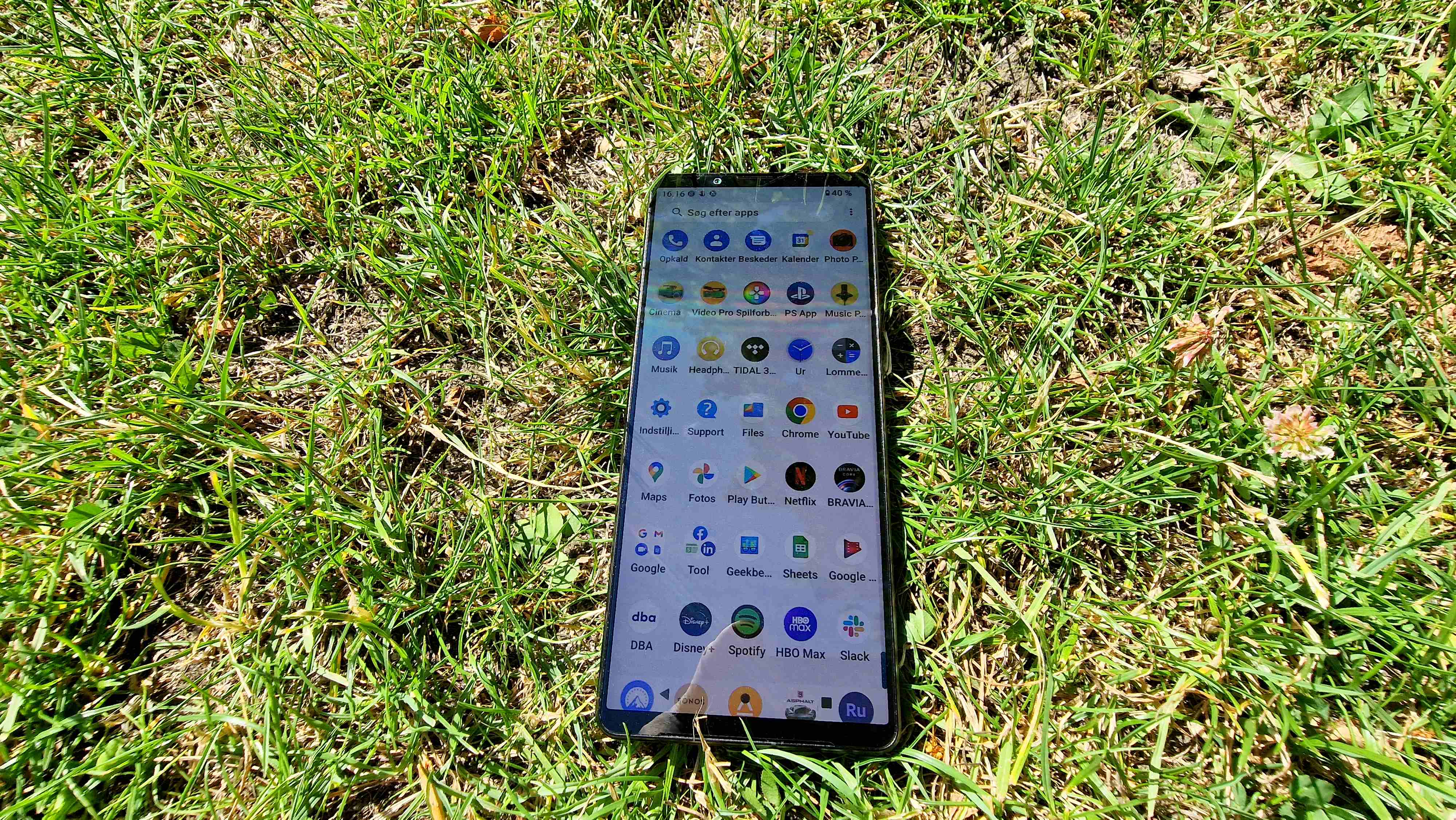 Sony Xperia 1 IV ligger i græsset med skærmen åben i app-skuffen.