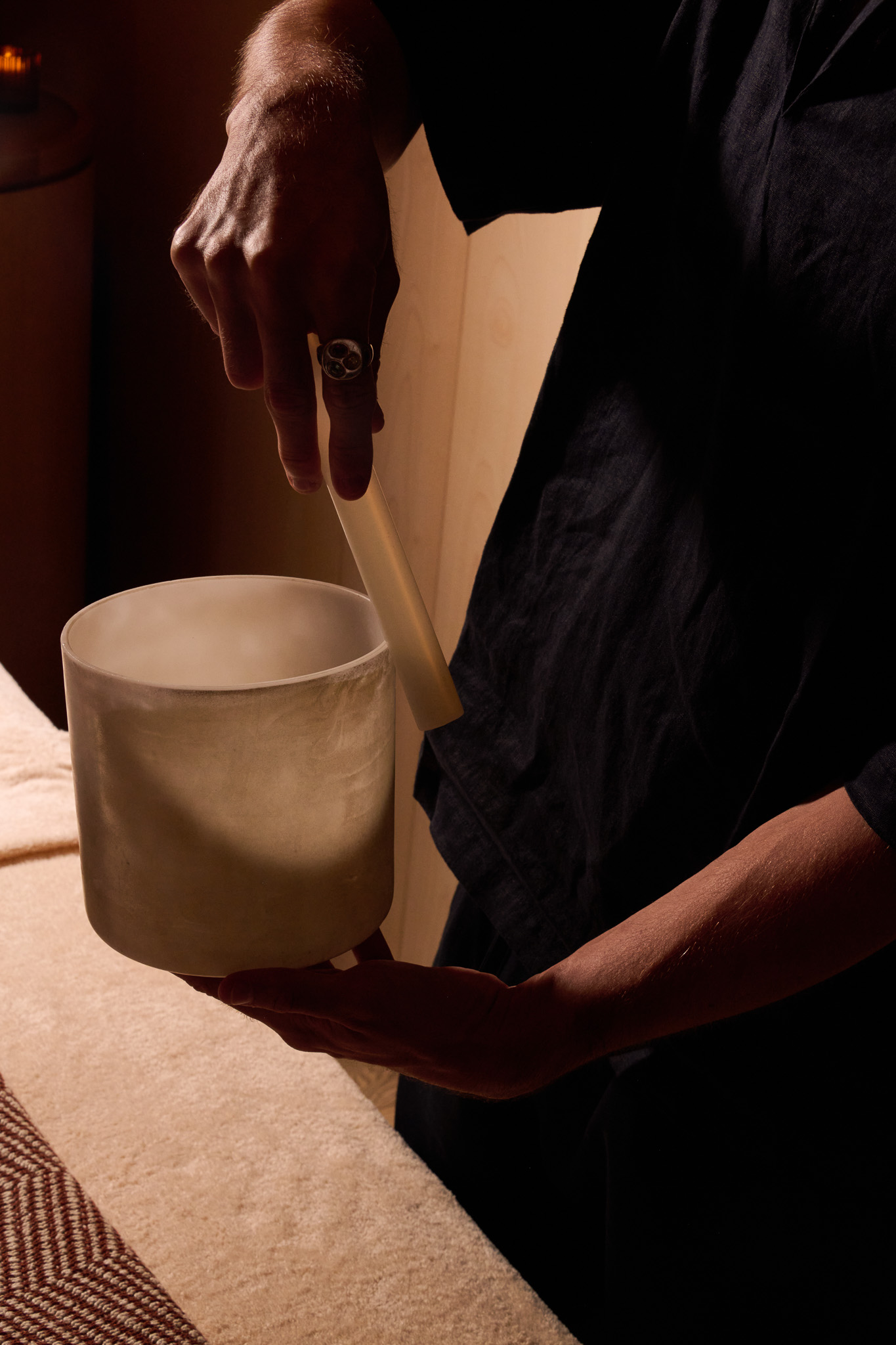 A spa treatment room shows a member of staff preparing an aromatherapy infusion in a ceramic container.