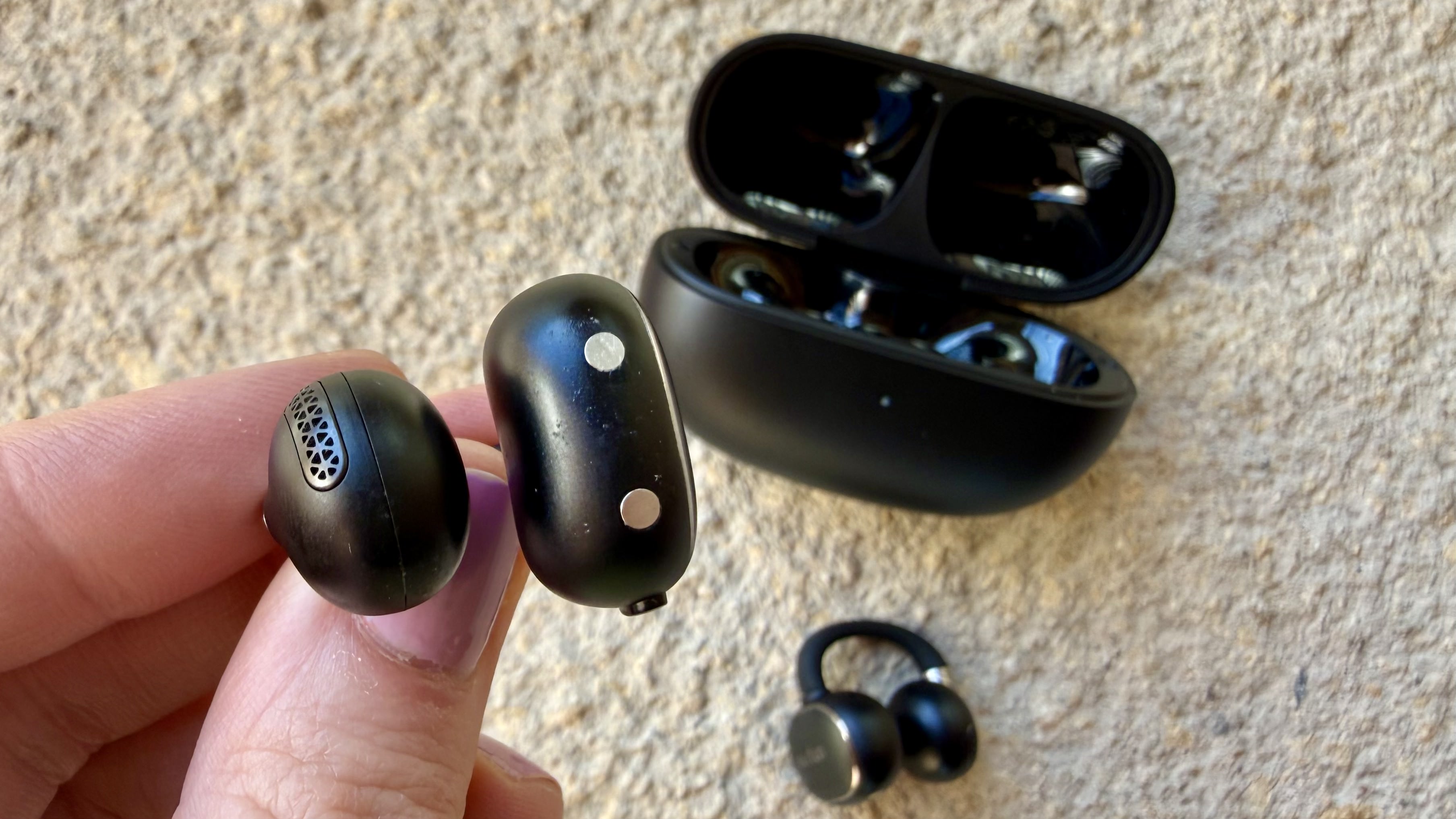 Someone holding one of the EarFun Clip 2 earbuds