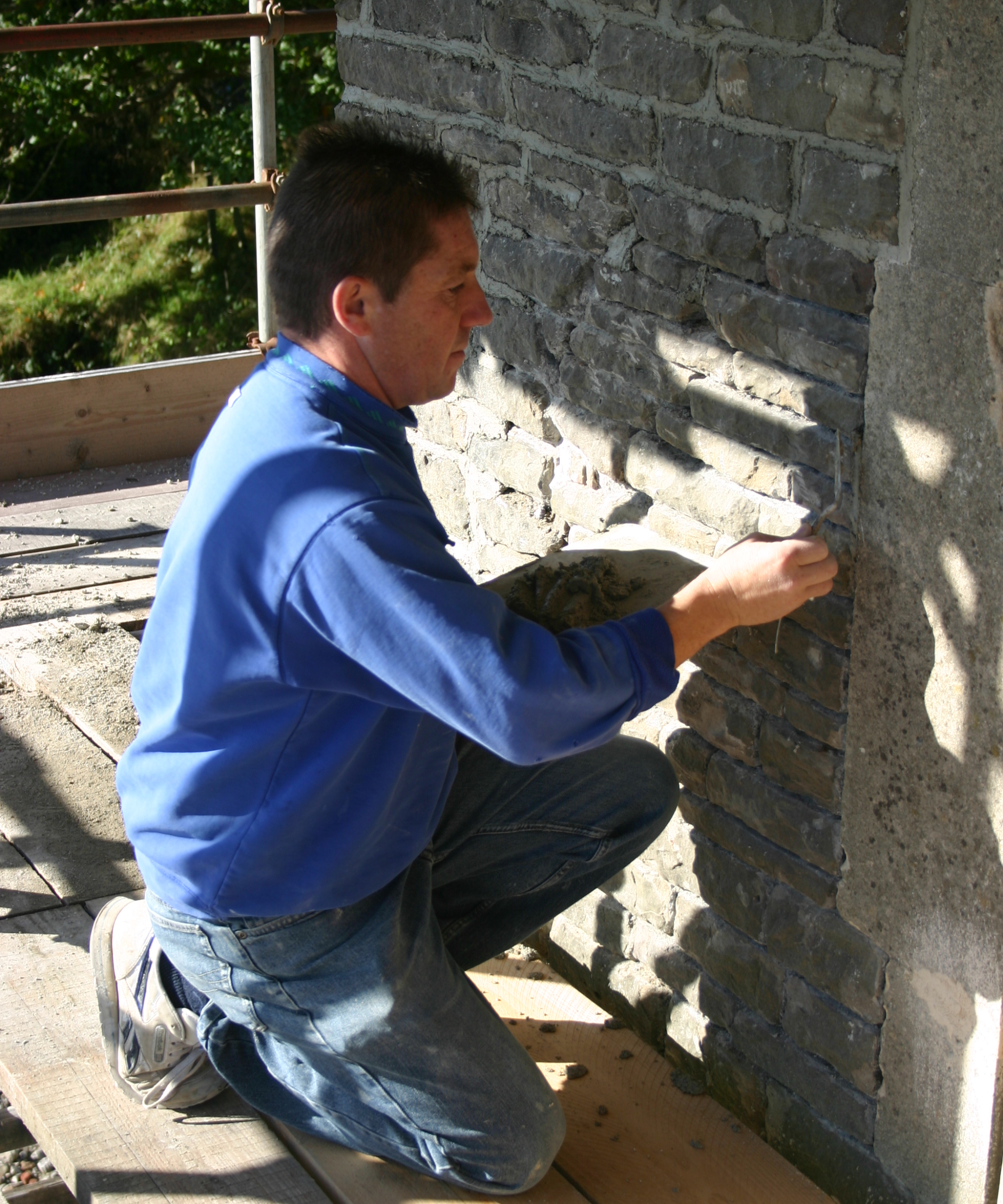 man repointing stonework on old building