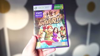 A photo of the game case for the Xbox 360 game Kinect Adventures in front of a gray wallpaper with a flower design.
