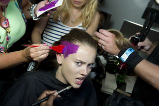 Model getting her make-up done and hair painted red