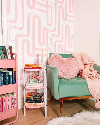 Pink geometric wallpaper surrounds colorful corner in small bedroom