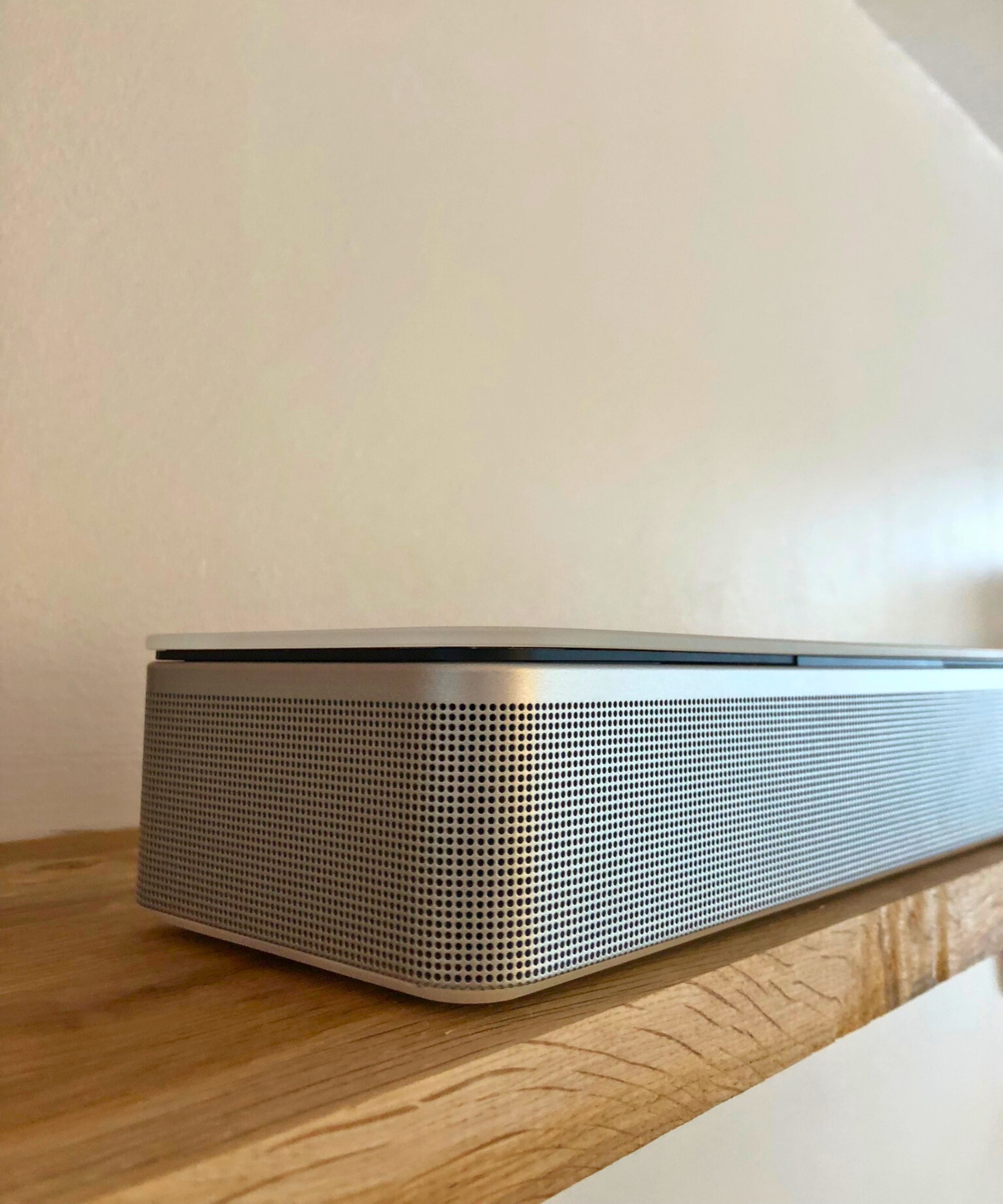 Closeup of the Bose Smart Ultra Soundbar on wooden shelf in Dan Fauzi's home.
