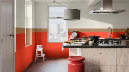 A kitchen with red, brown and white color blocked wall paint decor, kitchen island, red stool and grey ceiling pendant light