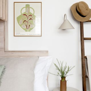 white wall with art and ladder shelving next to bed