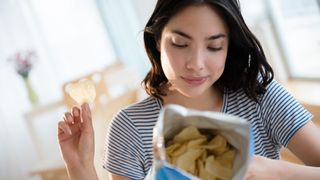 Woman reads the nutrition labelling on a bag of chips
