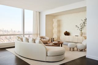 A neutral living room with curved sofa and matching furniture