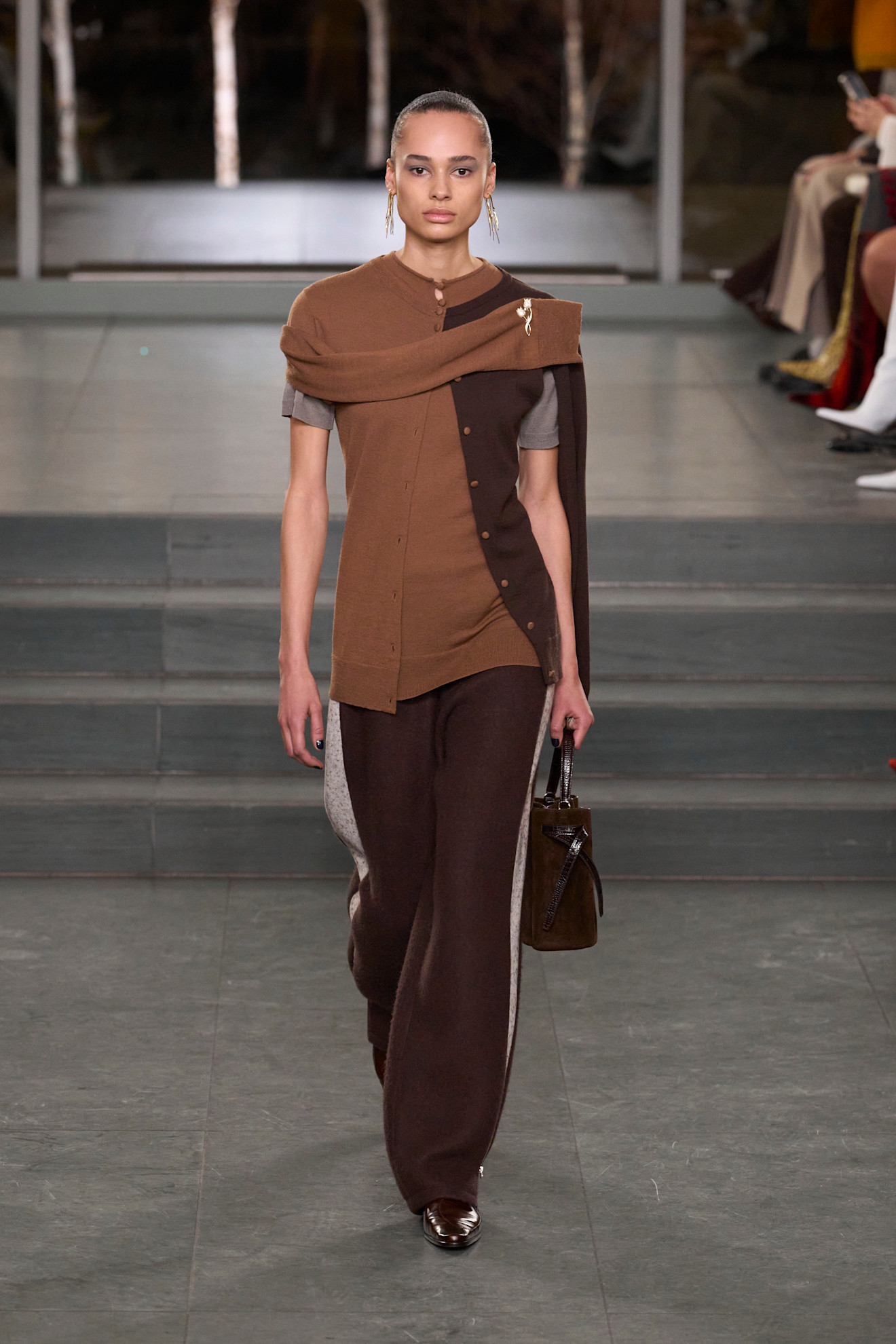 Tory Burch model walks the fall/winter 2025 runway wearing knitted track pants.