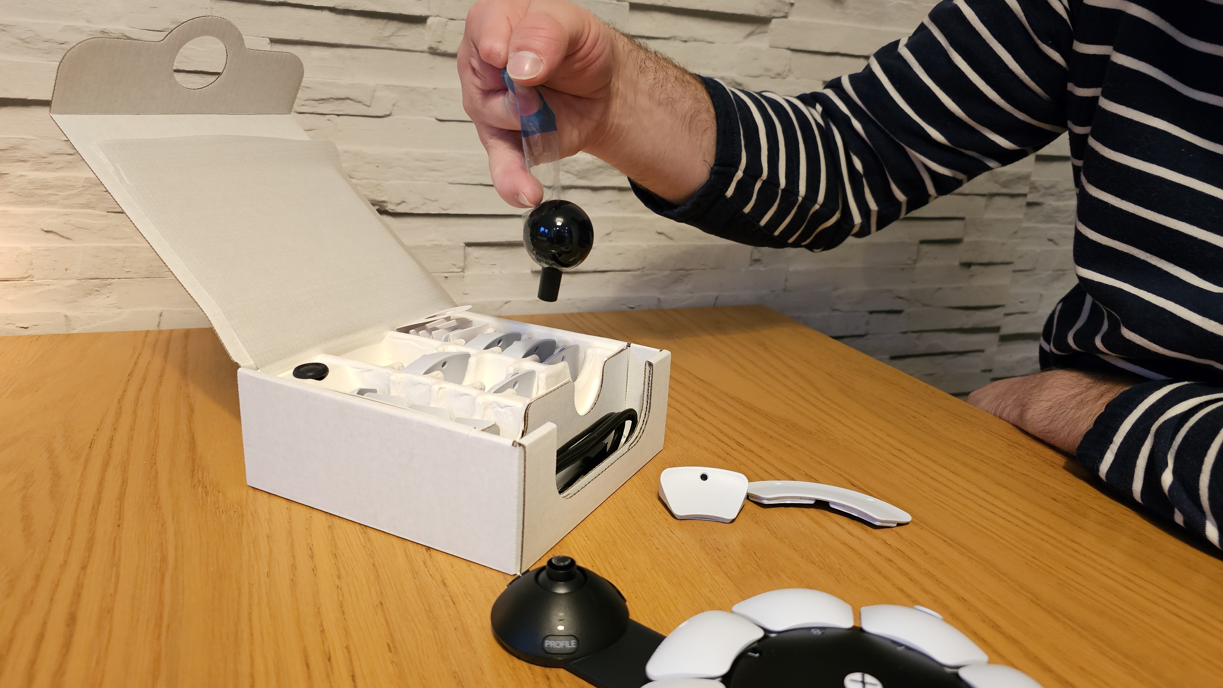 Unboxing the PlayStation Access controller with one hand on a wooden surface