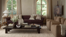 a living room with a large purple couch, two tan accent chairs, a low and long black coffee table, and a cream accent rug with subtle color details