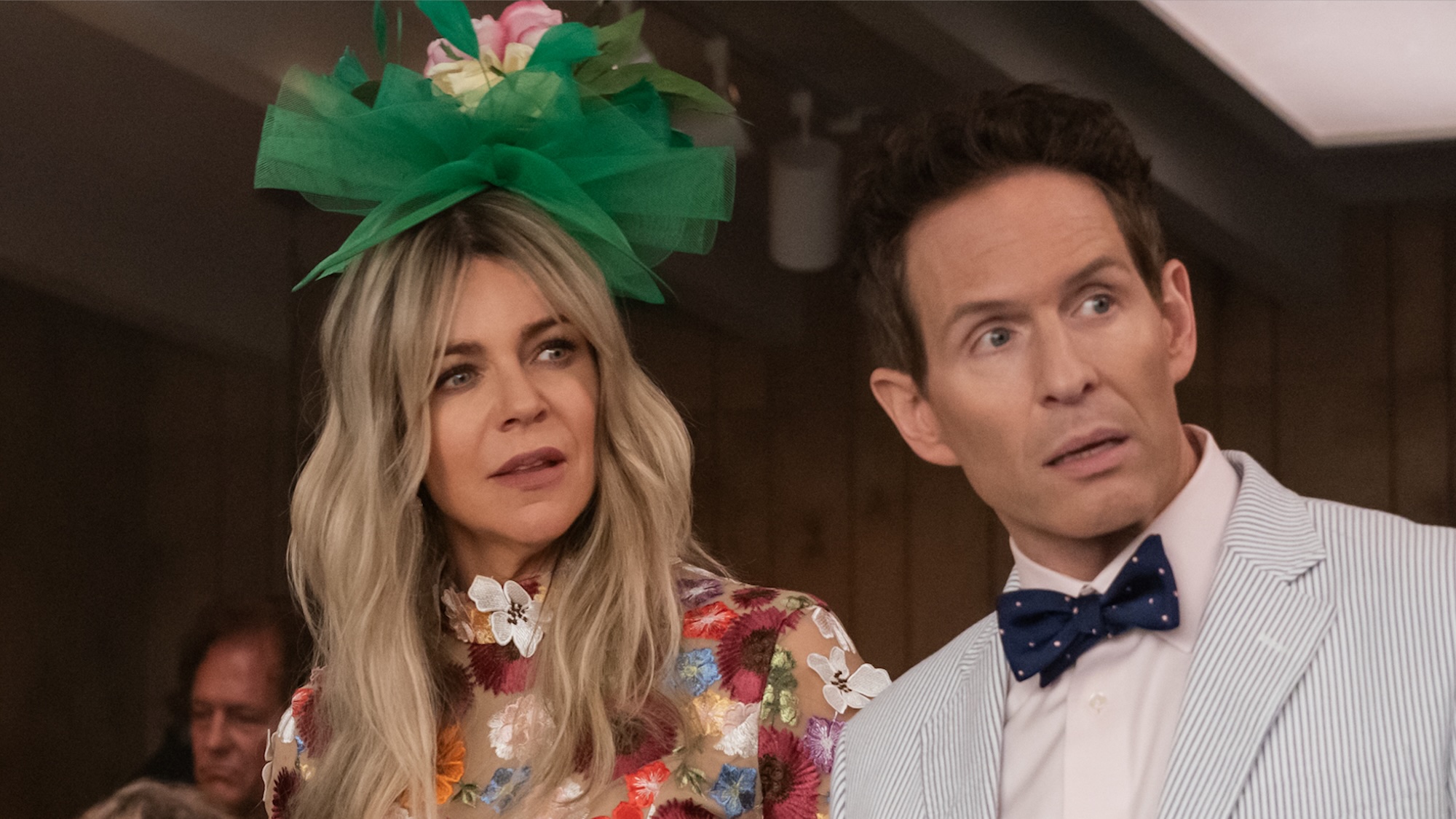 Dee in flowery green hat and dress next to Dennis in light blue suit at dog track in It's Always Sunny in Philadelphia Season 17