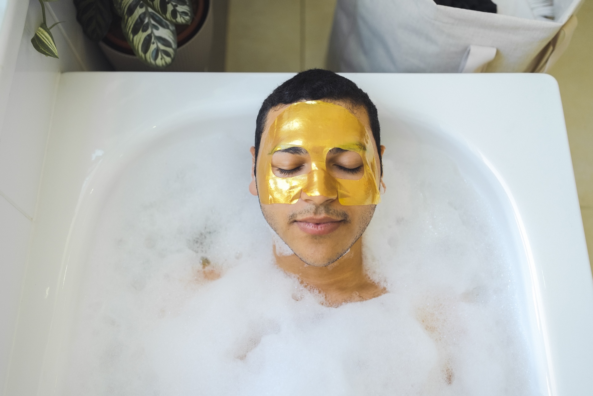 High angle view of man with facial mask relaxing in bathtub