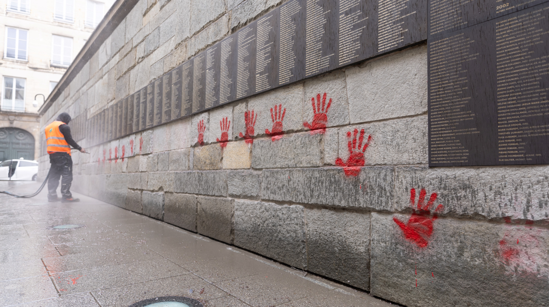 A city employee is at work to clean the "Wall of the Righteous" (Mur des Justes) covered with Red hands graffitis outside the Shoah memorial in Paris, on May 14, 2024, after the monument was vandalized overnight with the president of the Representative Council of French Jewish Institutions (CRIF) denouncing the act as antisemitic.