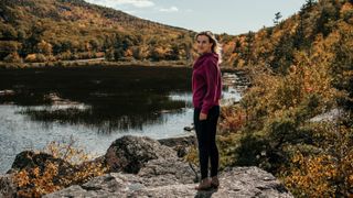 Full length of woman standing on rock by lake against mountains