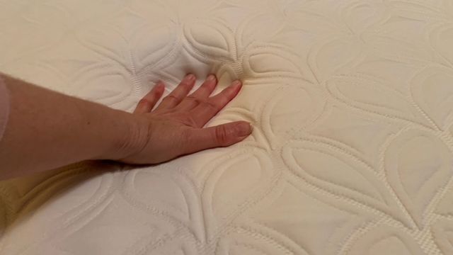 A close up of a hand touching the surface of the Cocoon by Sealy Chill mattress to test the temperature regulation