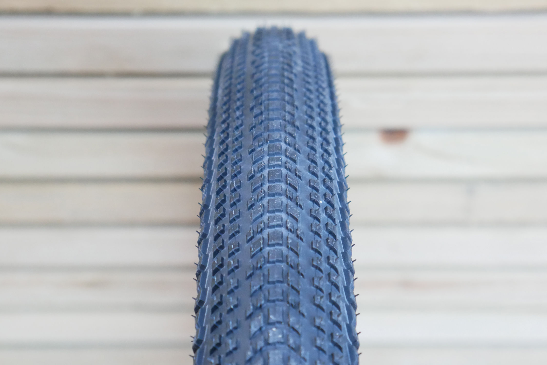 A close-up of the Hutchinson Touareg Race 45mm tread profile and shape with wooden cladding in the background