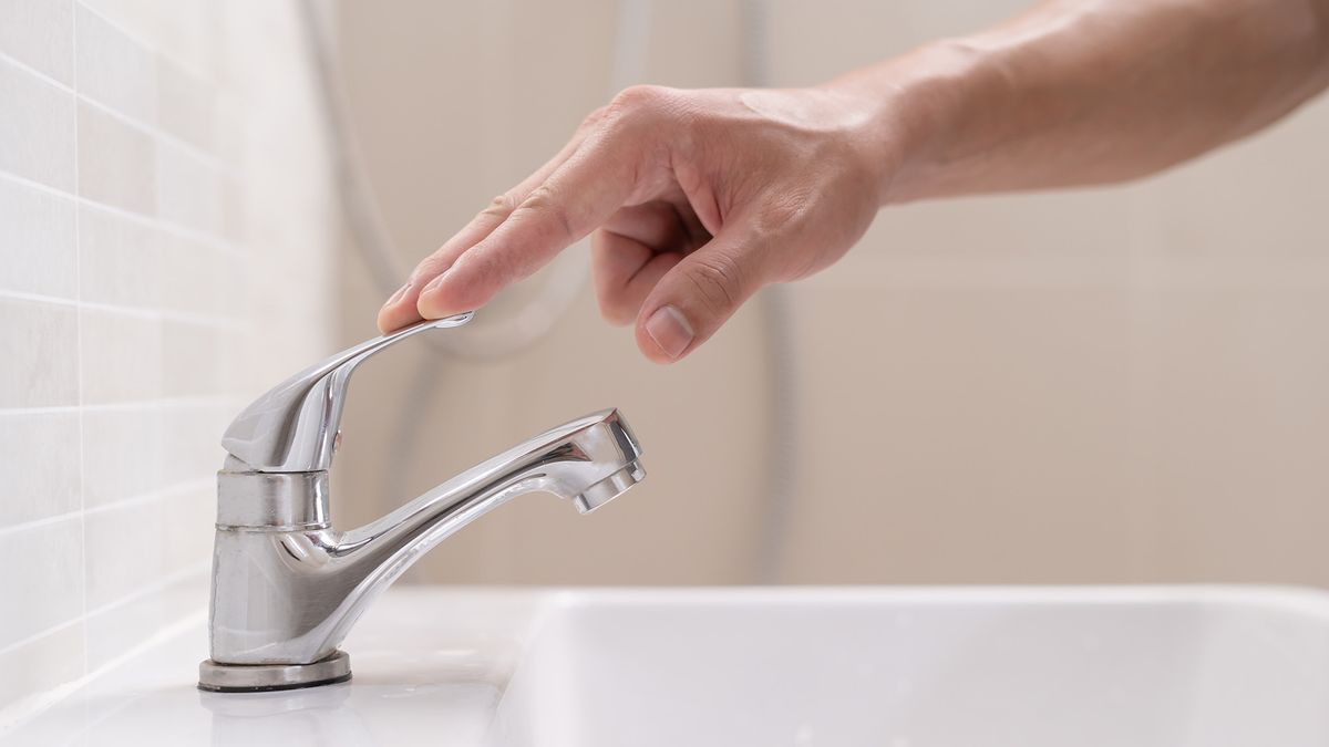 Man turning off bathroom faucet