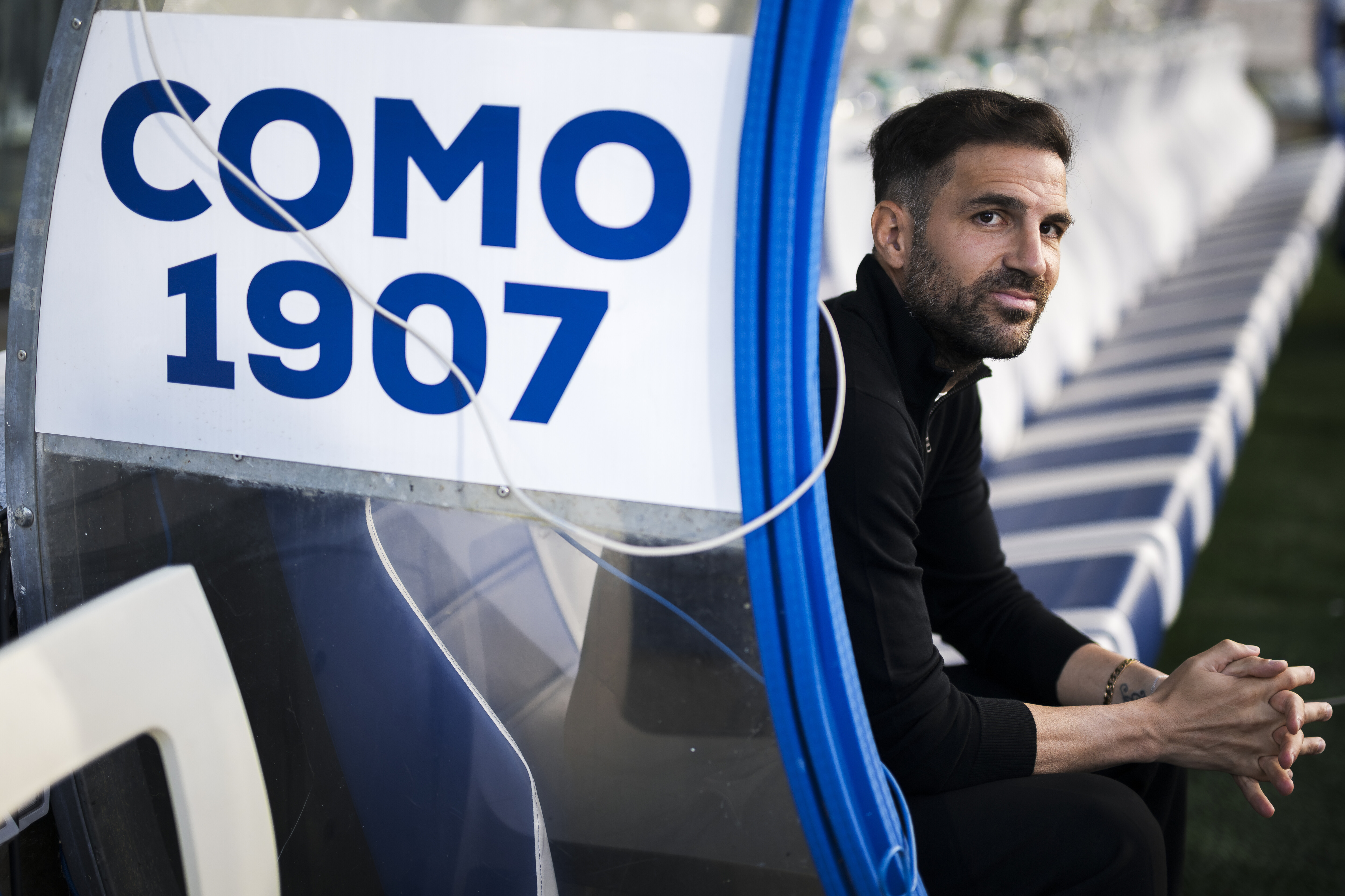 Cesc Fabregas smiles wanly at the camera from the Como dugout